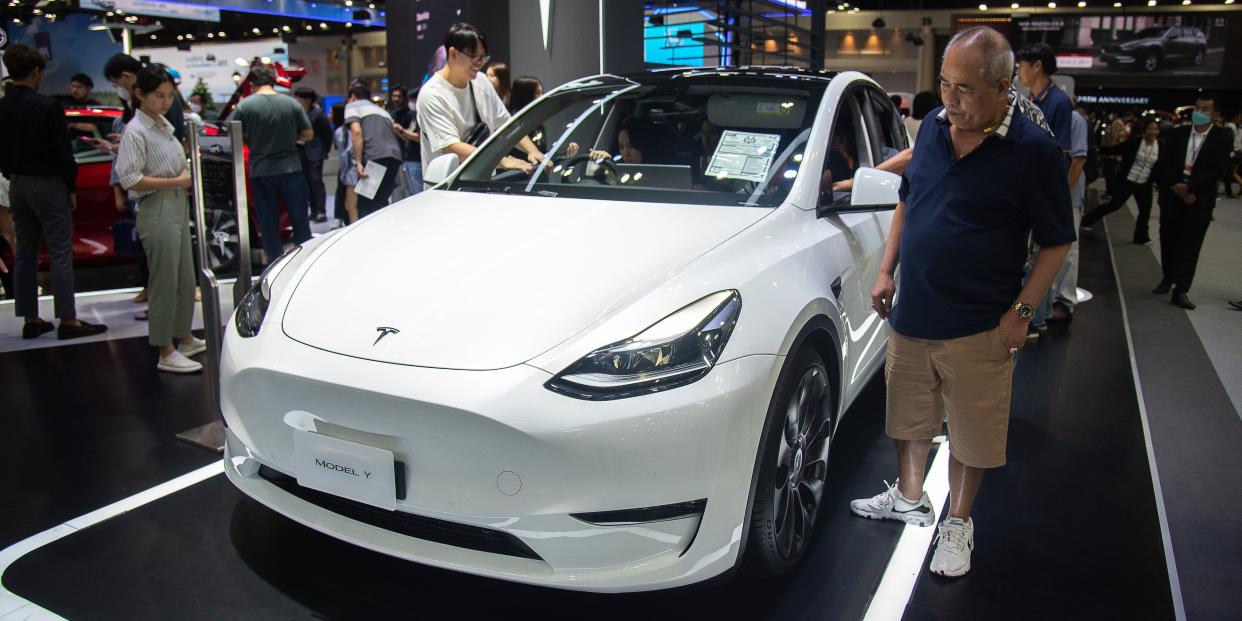 People inspect a Tesla Model Y car.