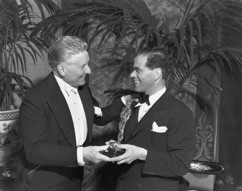 Fred Niblo(L) presents director Frank Capra(R) with his Academy Award for 1938's You Can't Take it with You.