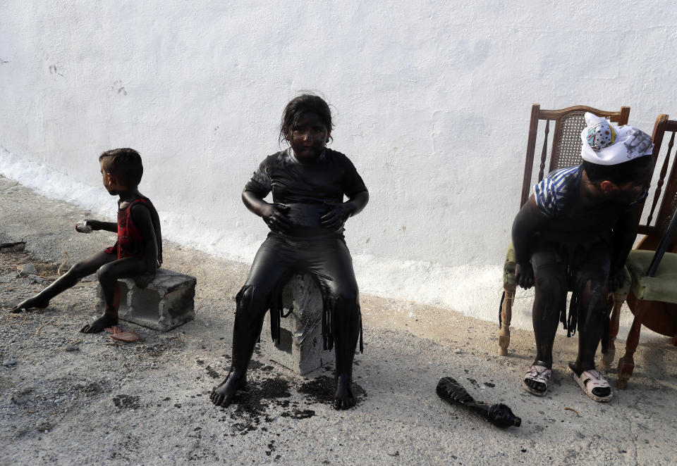 In this photo taken on Friday, Sept. 6, 2019, children painted with black grease take part in the traditional festivities of the Cascamorras festival in Baza, Spain. During the Cascamorras Festival, and according to an ancient tradition, participants throw black paint over each other for several hours every September 6 in the small town of Baza, in the southern province of Granada. The "Cascamorras" represents a thief who attempted to steal a religious image from a local church. People try to stop him, chasing him and throwing black paint as they run through the streets. (AP Photo/Manu Fernandez)