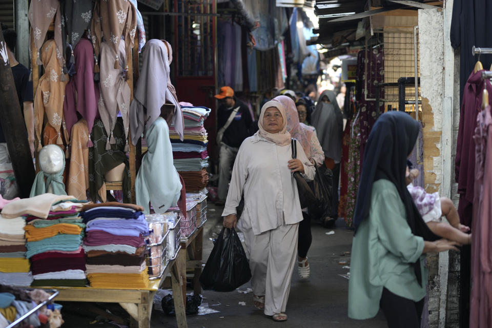 People walk at a market in Jakarta, Indonesia, Monday, Feb. 12, 2024. Indonesia, the world's third-largest democracy, will open its polls on Wednesday to nearly 205 million eligible voters in presidential and legislative elections, the fifth since Southeast Asia's largest economy began democratic reforms in 1998. (AP Photo/Achmad Ibrahim)