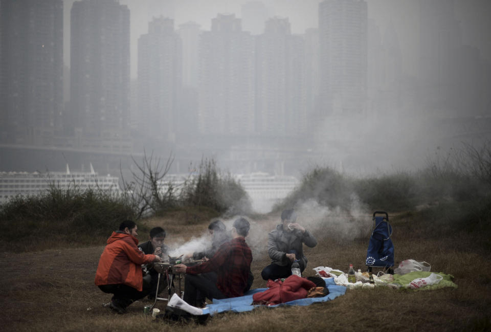 In this photo taken Sunday Feb. 23, 2014, residents barbecue along the river bank during a hazy day in southwest China's Chongqing municipality. Xinhua said that almost all provinces in central and east China have had serious air pollution since Friday, and that Beijing and five provinces in northern and eastern China had reported "severe smog." (AP Photo) CHINA OUT