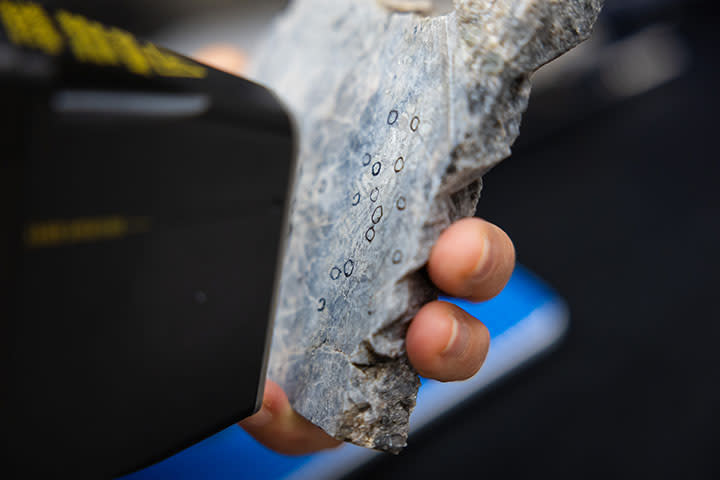 A closeup look at a piece of a rock where small crystals of suspected lithium are circled in black.