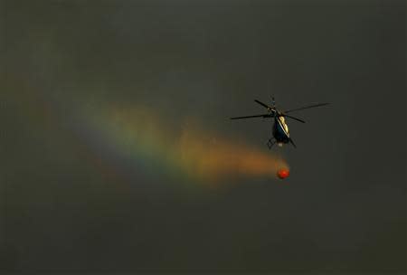 A fire fighting helicopter carries water as it fights a fire on a hillside near San Marcos, California May 14, 2014. REUTERS/Mike Blake