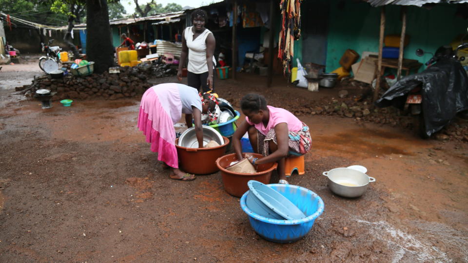 Women wash clothes at the house of Guinean wrestler Fatoumata Yarie Camara in Conakry, Guinea, Tuesday, July 20, 2021. A West African wrestler's dream of competing in the Olympics has come down to a plane ticket. Fatoumata Yarie Camara is the only Guinean athlete to qualify for these Games. She was ready for Tokyo, but confusion over travel reigned for weeks. The 25-year-old and her family can't afford it. Guinean officials promised a ticket, but at the last minute announced a withdrawal from the Olympics over COVID-19 concerns. Under international pressure, Guinea reversed its decision. (AP Photo/Youssouf Bah)