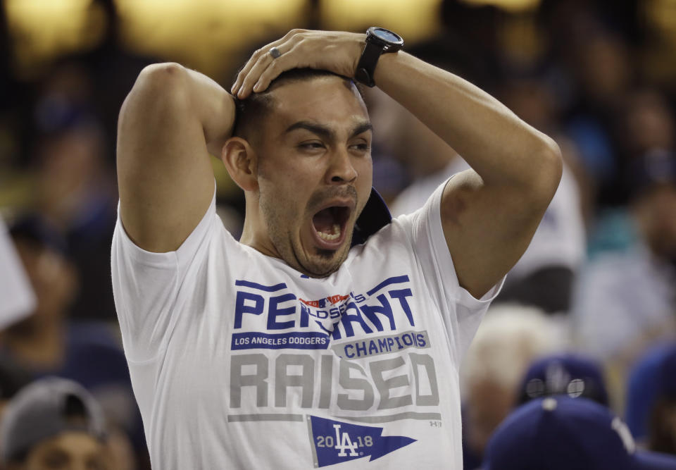 FILE - In this Oct. 26, 2018, file photo, a fan yawns before the start of the 17th inning in Game 3 of the World Series baseball game between the Boston Red Sox and Los Angeles Dodgers, in Los Angeles. Major League Baseball will start each extra inning this season by putting a runner on second base. This rule has been used since 2018 in the minor leagues, where it created more action and settled games sooner. (AP Photo/David J. Phillip, File)