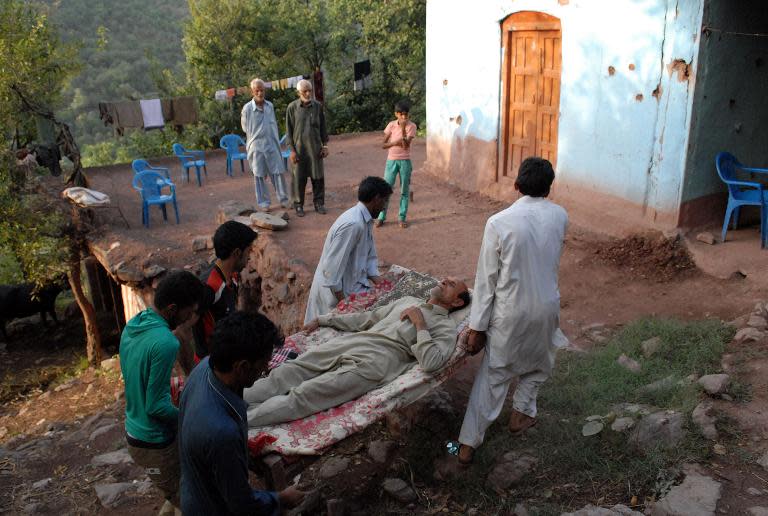 Pakistani men carry an injured victim following firing across the Line of Control (LoC) between Pakistan and India, in the Kotli sector of Pakistan-administrated Kashmir, on October 8, 2014
