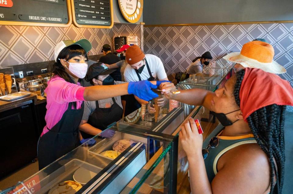 Salt & Straw’s Jackie Nelson hands a sample to midtown resident Georgia Russell at the opening day of the shop on R Street in midtown Sacramento on Friday, Sept. 2, 2022. Russell was considering several of the store’s zany flavors – including strawberry balsamic, pear and bleu cheese, or spiced goat cheese pumpkin pie – while waiting in line.