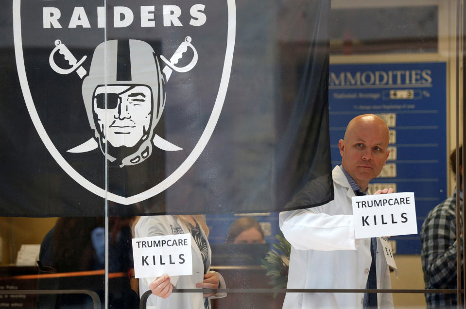 <p>Beside a Raiders football team flag, healthcare activists hold up signs while occupying the office of Senator Dean Heller to protest the Republican healthcare bill at the Capitol in Washington, D.C., July 10, 2017. (Photo: Kevin Lamarque/Reuters) </p>