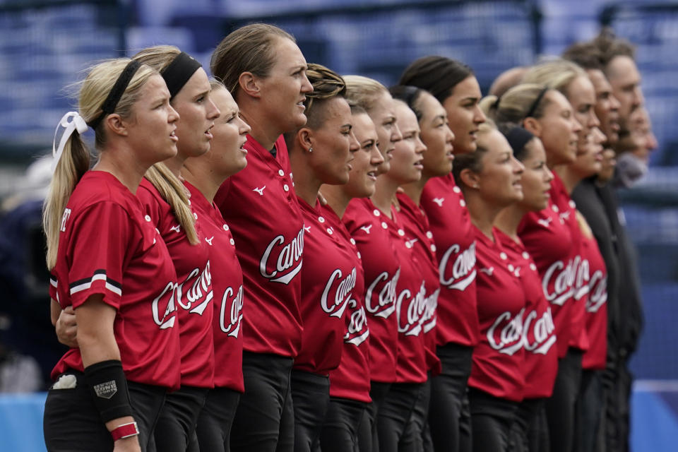 Members of team Canada stand during the playing of their national anthem ahead of a softball game against Mexico at the 2020 Summer Olympics, Tuesday, July 27, 2021, in Yokohama, Japan (AP Photo/Sue Ogrocki)