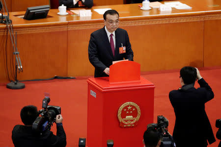 Chinese Premier Li Keqiang drops his ballot during a vote on a constitutional amendment lifting presidential term limits, at the third plenary session of the National People's Congress (NPC) at the Great Hall of the People in Beijing, China March 11, 2018. REUTERS/Jason Lee