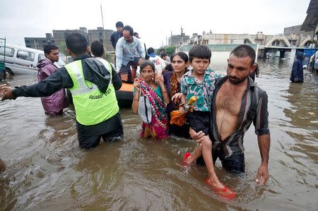 Fire officials and rescuers evacuate people from a flooded neighbourhood after heavy rains in Ahmedabad. REUTERS/Amit Dave