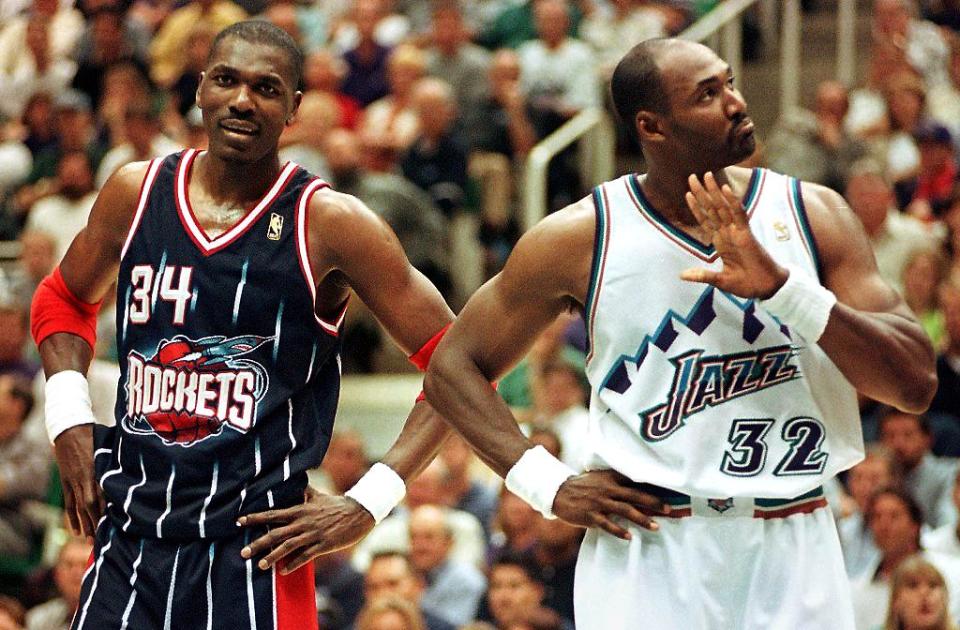 Karl Malone of the Utah Jazz (R) and Hakeem Olajuwon of the Houston Rockets stand together during a break in game two of the NBA Western Conference Finals 21 May at the Delta Center in Salt Lake City, Utah. The Jazz won 104-92. AFP PHOTO/DOUG COLLIER (Photo by DOUG COLLIER / AFP)        (Photo credit should read DOUG COLLIER/AFP/Getty Images)