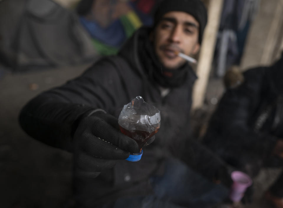 A migrant shows an improvised tea mug while bracing against harsh winter weather inside an abandoned hangar near the Hungarian border, outside of the village of Majdan, Serbia, Tuesday, Jan. 11, 2022. Hungary's nationalist prime minister, Viktor Orban, is keen to use the threat of migrants at his country's southern border to give him an advantage in upcoming elections. But the scale of migration pressure claimed by Orban is drawn into question by statistics from neighboring Serbia and the European Union's border agency. (AP Photo/Bela Szandelszky)