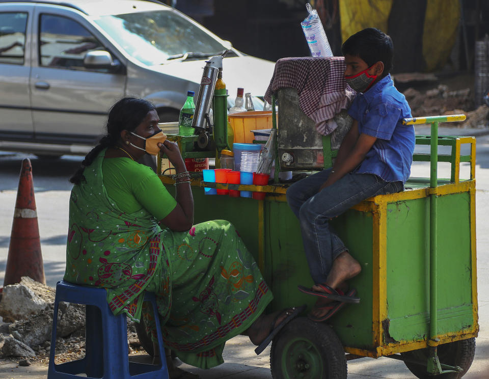 Indian vendors wearing face masks as a precaution against the coronavirus waits for customer while selling lemon soda on a street in Hyderabad, India, Sunday, Dec. 13, 2020. (AP Photo/Mahesh Kumar A.)