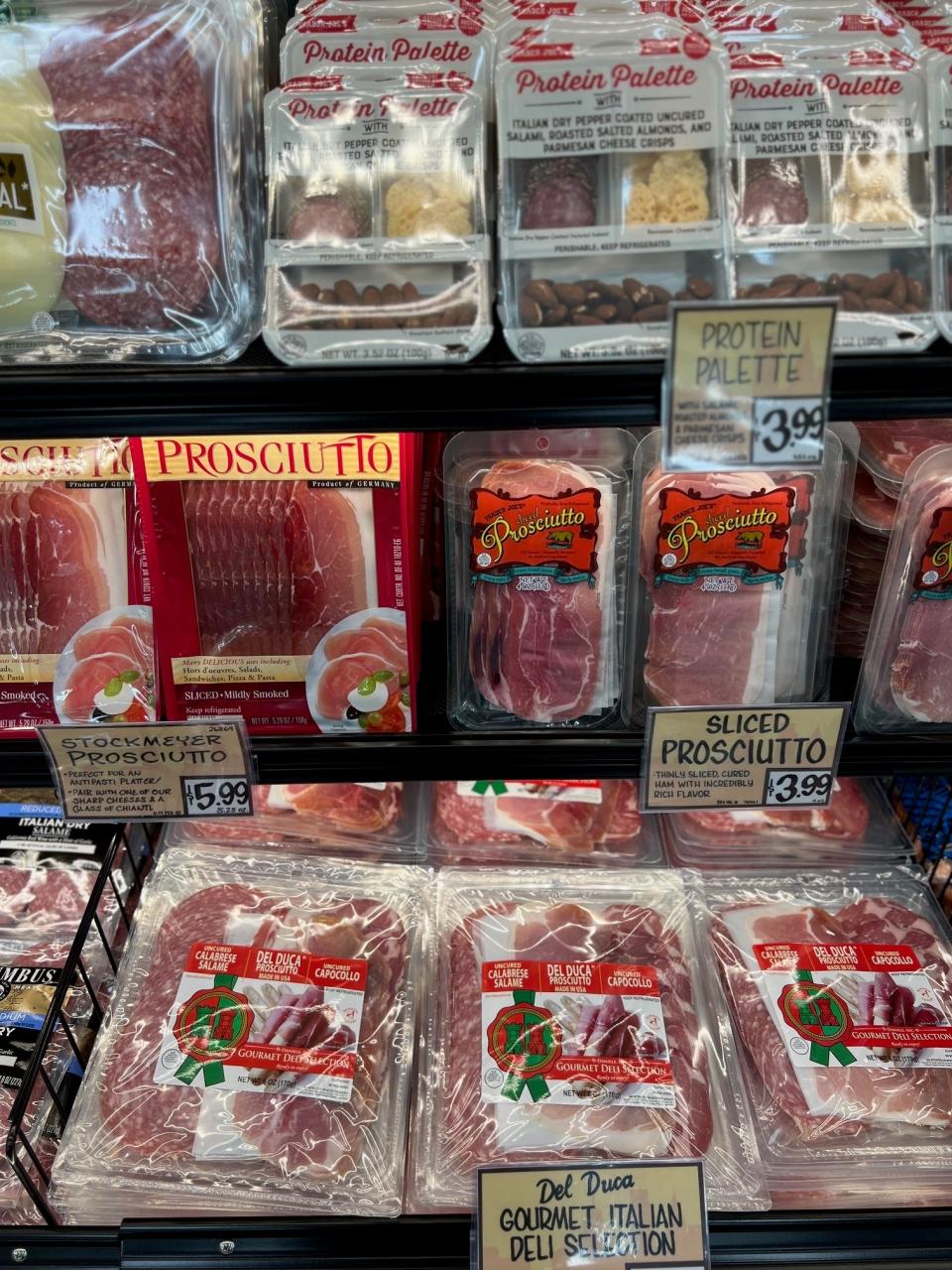 Refrigerated display with various packaged meats including prosciutto and Protein Palette snack boxes