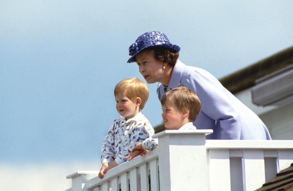 June 1987: The queen stands behind two young boys as they all look at something.