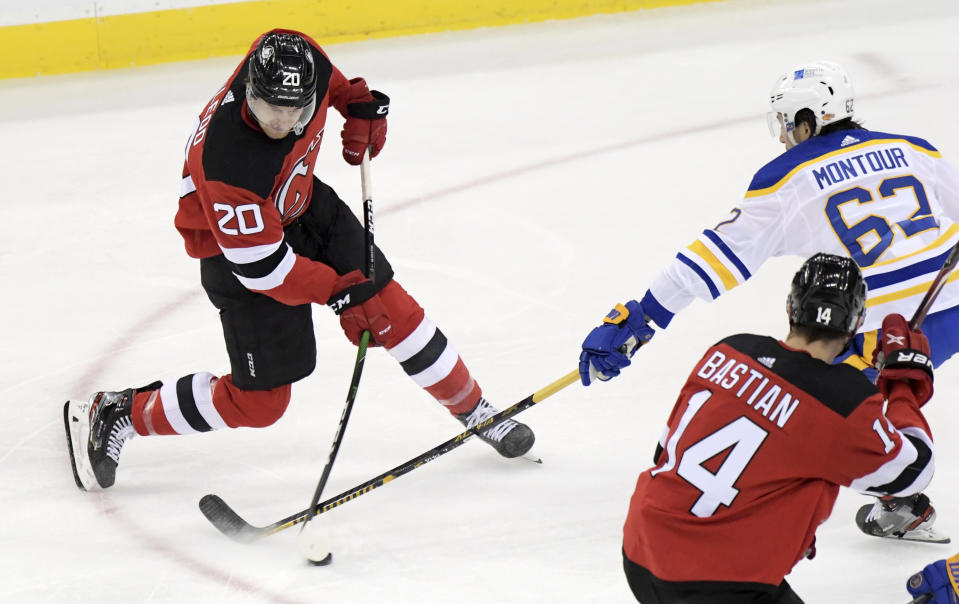 New Jersey Devils center Michael McLeod (20) takes a shot as Buffalo Sabres defenseman Brandon Montour (62) defends during the second period of an NHL hockey game Tuesday, Feb. 23, 2021, in Newark, N.J. (AP Photo/Bill Kostroun)