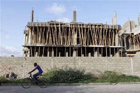 A man rides a bicycle past a building under construction in the Victoria Island district in Nigeria's commercial capital Lagos September 6, 2013. REUTERS/Akintunde Akinleye