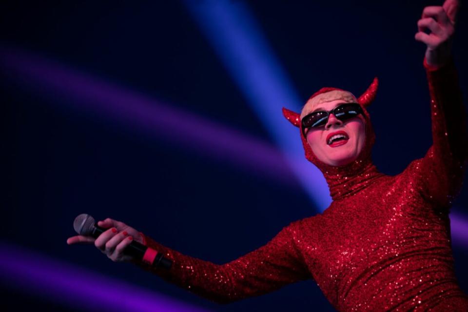 A drag queen dressed in a red sequinned devil outfit 