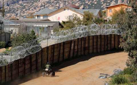 A US Customs and Border Patrol agent travels along the border wall between the US and Mexico near Tecate, California - Credit: &nbsp;MIKE BLAKE/Reuters