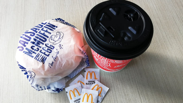 wrapped sausage mcmuffin wth coffee cup