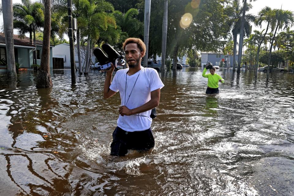 FILE - James Richard and Katherine Arroyo trudge through the water in Hollywood, Fla., on April 13, 2023. Over 25 inches of rain fell in South Florida since Monday, causing widespread flooding. (Mike Stocker/South Florida Sun-Sentinel via AP, File)