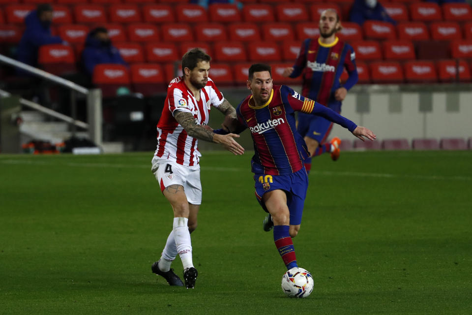 Barcelona's Lionel Messi, right, fights for the ball with Athletic Bilbao's Inigo Martinez during the Spanish La Liga soccer match between FC Barcelona and Athletic Bilbao at the Camp Nou stadium in Barcelona, Spain, Sunday, Jan. 31, 2021. (AP Photo/Joan Monfort)