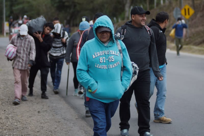 People, part of a caravan of migrants heading toward the United States, walk along a road in Agua Caliente