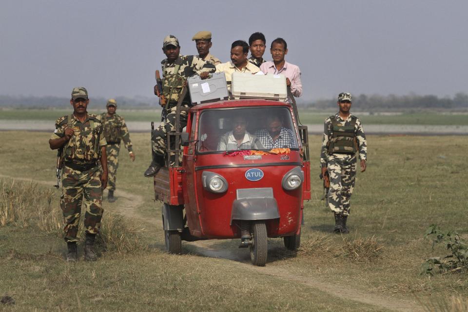 A polling officer carrying electronic voting machines arrives accompanied by security men in a three wheeler on the eve of parliamentary elections at Misamora Sapori, an island in the River Brahmaputra in Assam state, India, Sunday, April 6, 2014. (AP Photo/Anupam Nath)