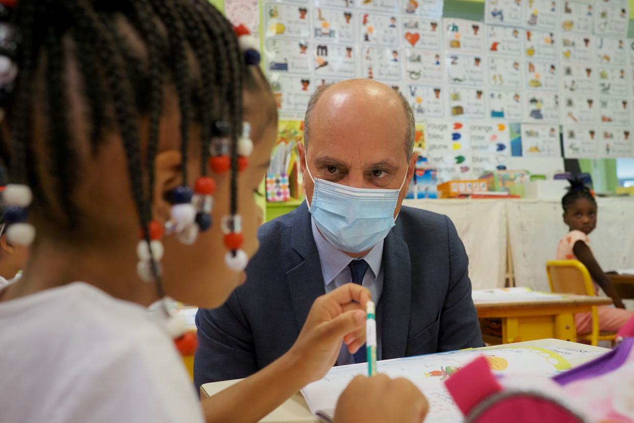 French Education Minister Jean-Michel Blanquer talks with a child for the first day at the elementary school of Louis de Frontenac in Chateauroux, central France, on Tuesday, Sept.1, 2020. Millions of French children starting going back to class Tuesday despite a recent rise in virus infections, in a nationwide experiment aimed at bridging inequalities and reviving the economy.