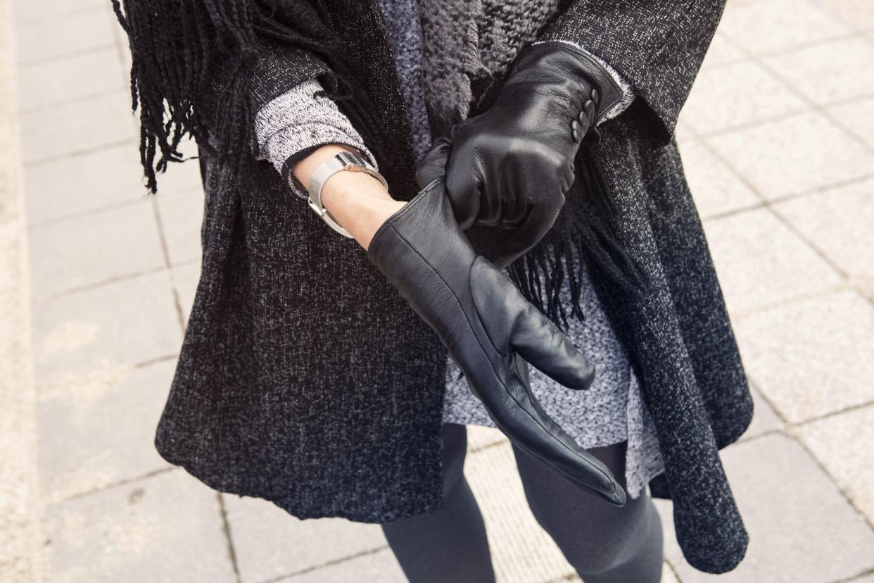 close-up of woman standing in the street putting on her black leather gloves