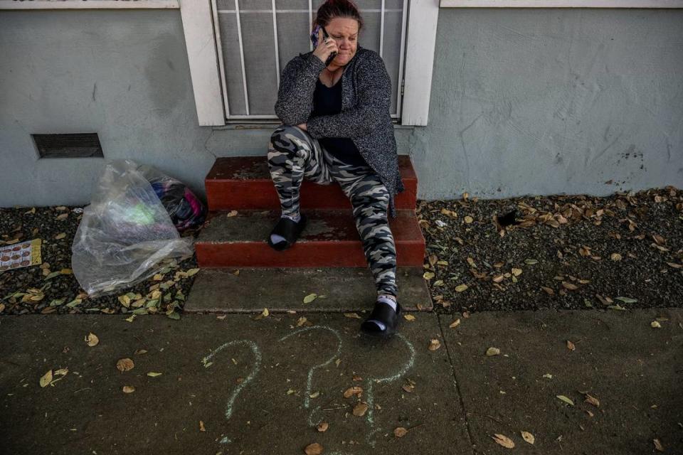 Kristi Phillips listens on Monday to her son explain why he skipped school while she awaits Sheriff’s deputies enforcing an order evicting her and her son from an apartment where they had been living. At her feet are three question marks her friends had written in chalk on the walkway about her housing situation.