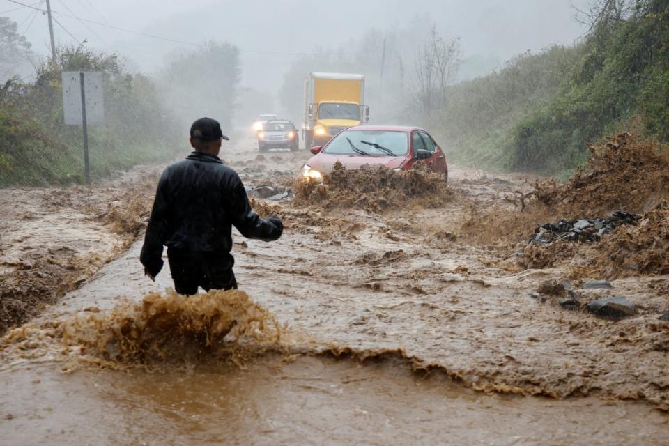 A local resident walks out into fast-flowing waters to assist a stranded driver in a stretch of flooded road as Tropical Storm Helene strikes, on the outskirts of Boone, N.C., on Friday.  