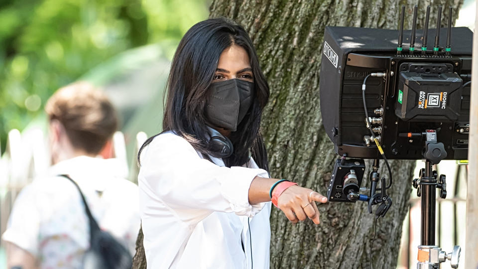 Ishana Shyamalan pointing at something while looking at a screen on a filming set