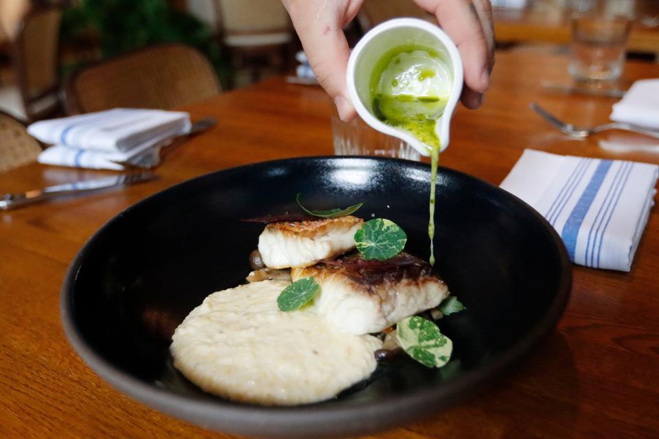 Executive Chef of the Drayton Hotel Benjamin Murray pours a sauce on the Snapper and Grits at the St. Neo's Brasserie in the Drayton Hotel in Savannah, GA Saturday, May 28, 2022.