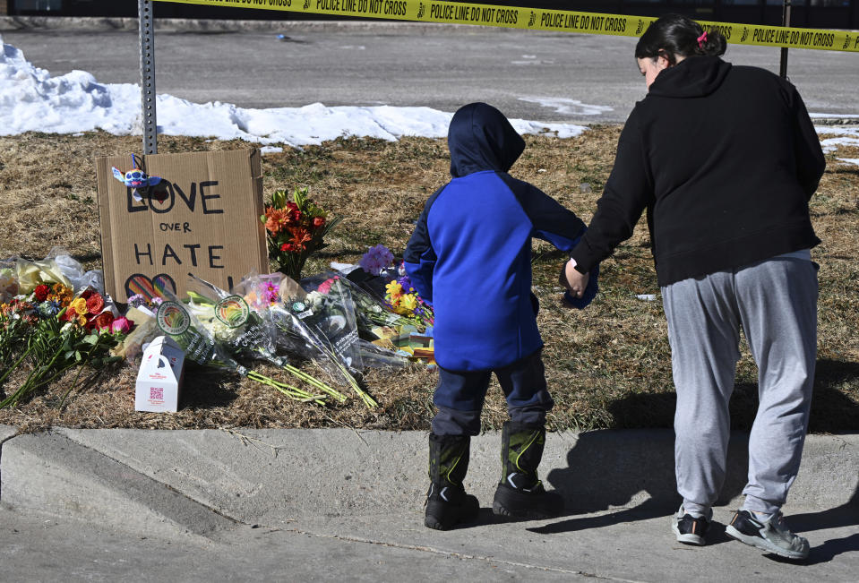 Kristen Morris and her son, Kai Morris, 6, walk away from a memorial Sunday morning, Nov. 20, 2022, for the victims of a shooting at Club Q in Colorado Springs, Colo., on Saturday night. Morris wanted to share kindness and she and her two sons placed painted crosses on the memorial. (Christian Murdock/The Gazette via AP)