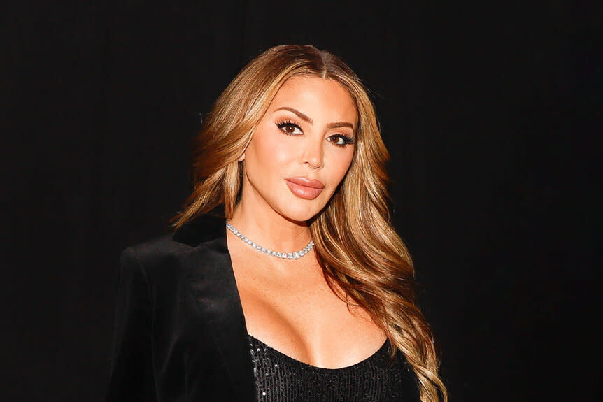 Larsa Pippen wearing a black blazer standing in front of a black backdrop.