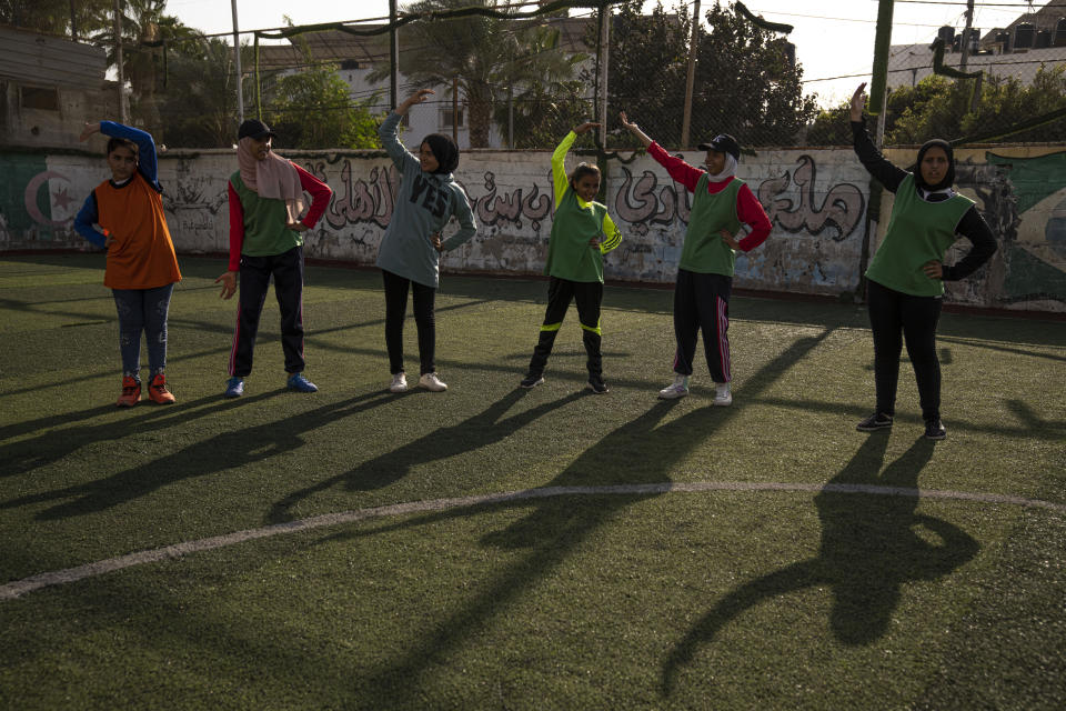 Palestinian girls stretch during a soccer training session at the Beit Hanoun Al-Ahli Youth Club's ground in the northern Gaza strip, Tuesday, Oct. 29, 2022. Women's soccer has been long been neglected in the Middle East, a region that is mad for the men's game and hosts the World Cup for the first time this month in Qatar. (AP Photo/Fatima Shbair)