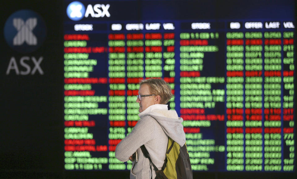 A woman looks at display boards at the Australian Stock Exchange in Sydney, Australia, Monday, May 6, 2019. Shares tumbled in Asia after President Donald Trump threatened to impose more tariffs on China, spooking investors who had been expecting good news this week on trade. (AP Photo/Rick Rycroft)