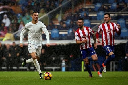 Real Madrid's Cristiano Ronaldo runs with the ball past Sporting Gijon's Manuel Castellano Castro "Lillo" and Ismael Lopez. Real Madrid v Sporting Gijon - Spanish La Liga Santander- Santiago Bernabeu Stadium, Madrid, Spain - 26/11/16. REUTERS/Susana Vera