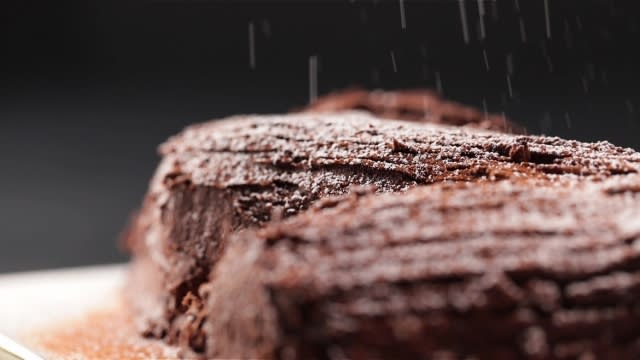 Dusting log cake with icing sugar