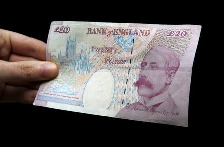 A woman poses with a Bank of England twenty pound note bearing the image of Edward Elgar in Edinburgh, Scotland June 29, 2010. REUTERS/David Moir