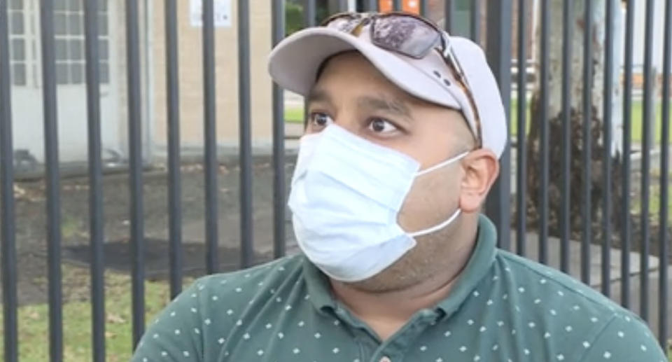 Jicky Mathew wears a mask as he speaks to a reporter outside Taree West primary school.