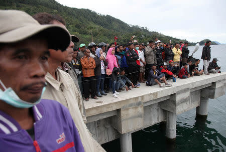 Local residents and relatives of missing passengers from a ferry accident on Lake Toba, a popular tourist destination, wait on the dock at Tigaras Port, Simalungun, North Sumatra, Indonesia June 19, 2018. REUTERS/Albert Damanik
