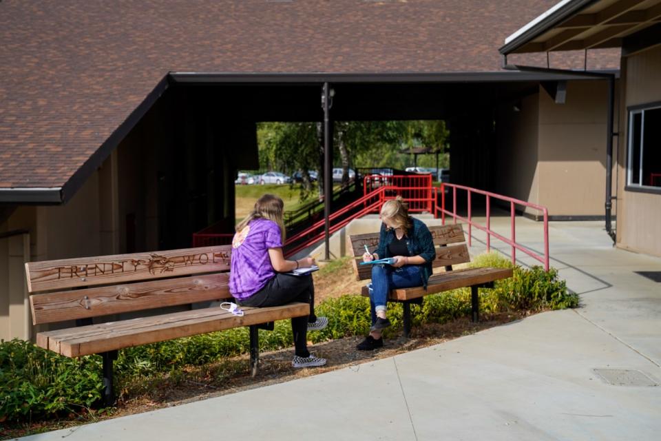 Students Josalyn Spagel and Emma Case, both 15, work together outside their classroom at Trinity High School.