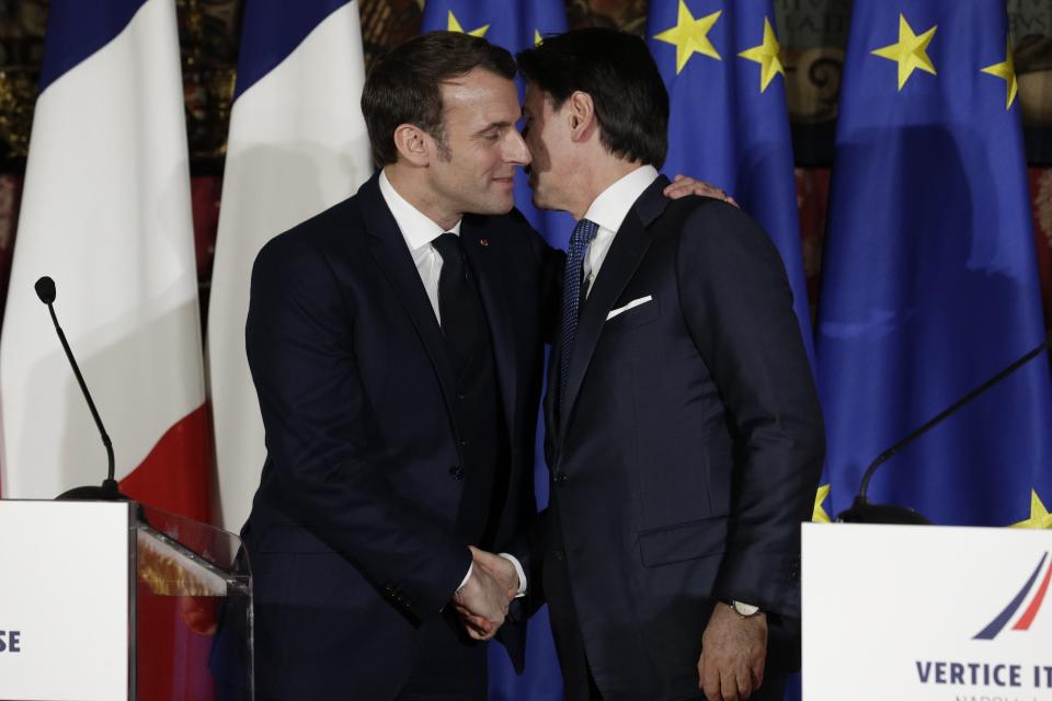 FILE - In this Thursday, Feb. 27, 2020 file photo, French President Emmanuel Macron, left, puts his arm around the shoulder of Italian Premier Giuseppe Conte and gives him a kiss on both cheeks during a joint press conference on the occasion of a French-Italian summit in Naples, southern Italy. French President Emmanuel Macron leaned in to give Premier Giuseppe Conte the Italian double-cheek kiss not just once, but at two separate moments during a Franco-Italian summit in Naples this week. It was much more than a greeting; it was a signal to citizens not to fear their neighbors as a new virus from China spreads, with Italy established as Europe’s hotspot. (AP Photo/Andrew Medichini, File)