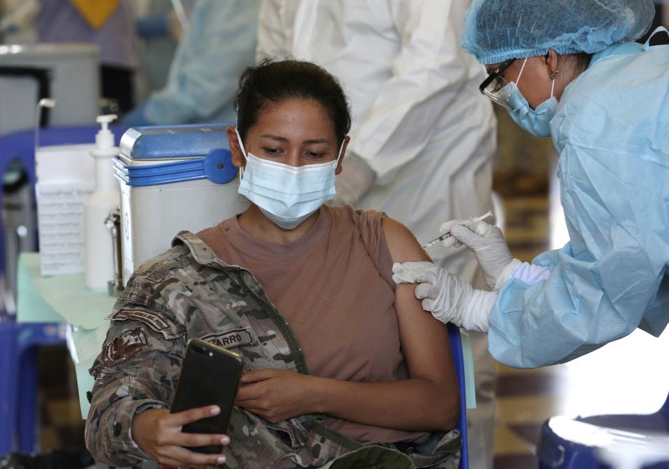 An Air Force member takes a selfie while getting her shot of the Pfizer vaccine for COVID-19 at a military base in Lima, Peru, Monday, March 8, 2021. (AP Photo/Martin Mejia)