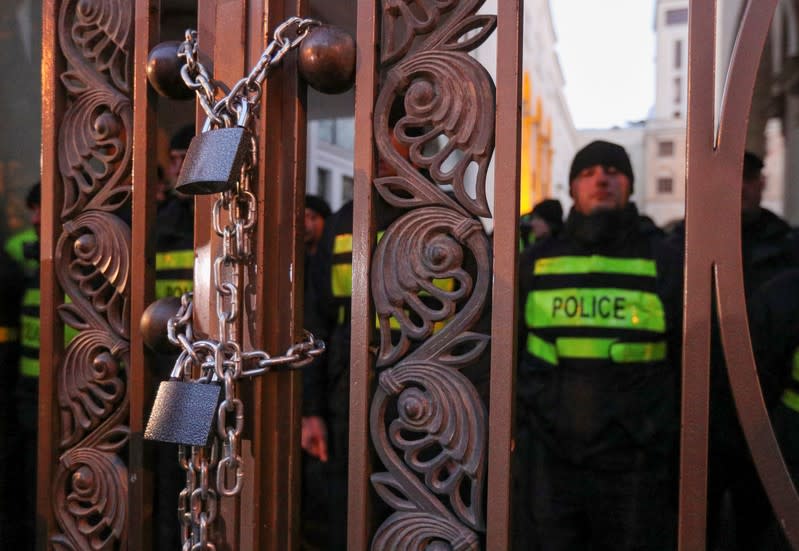 Opposition supporters chain the gate of the parliament during a rally to protest against the government and demand an early parliamentary election, in Tbilisi