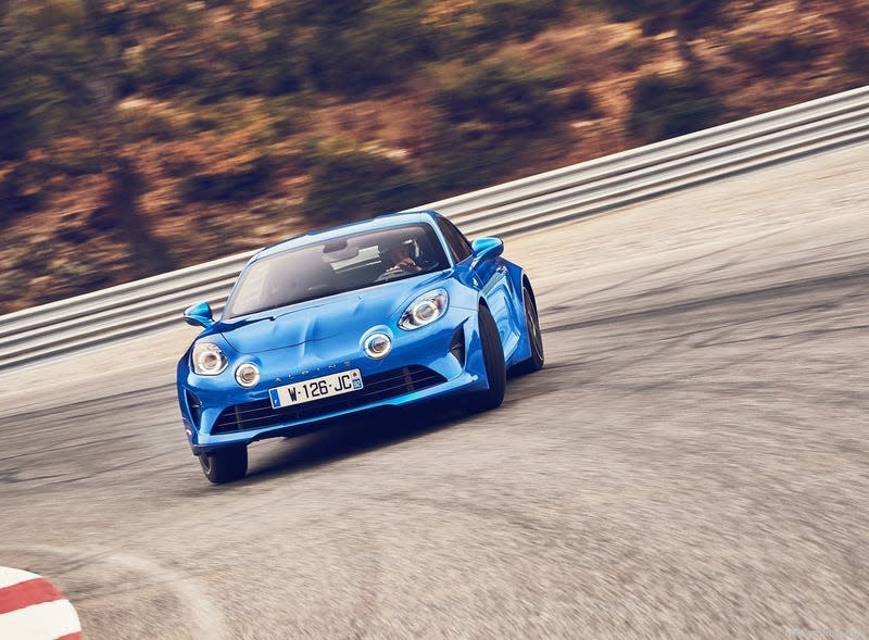 a blue Alpine A110 sliding through a corner on a racetrack looking epic