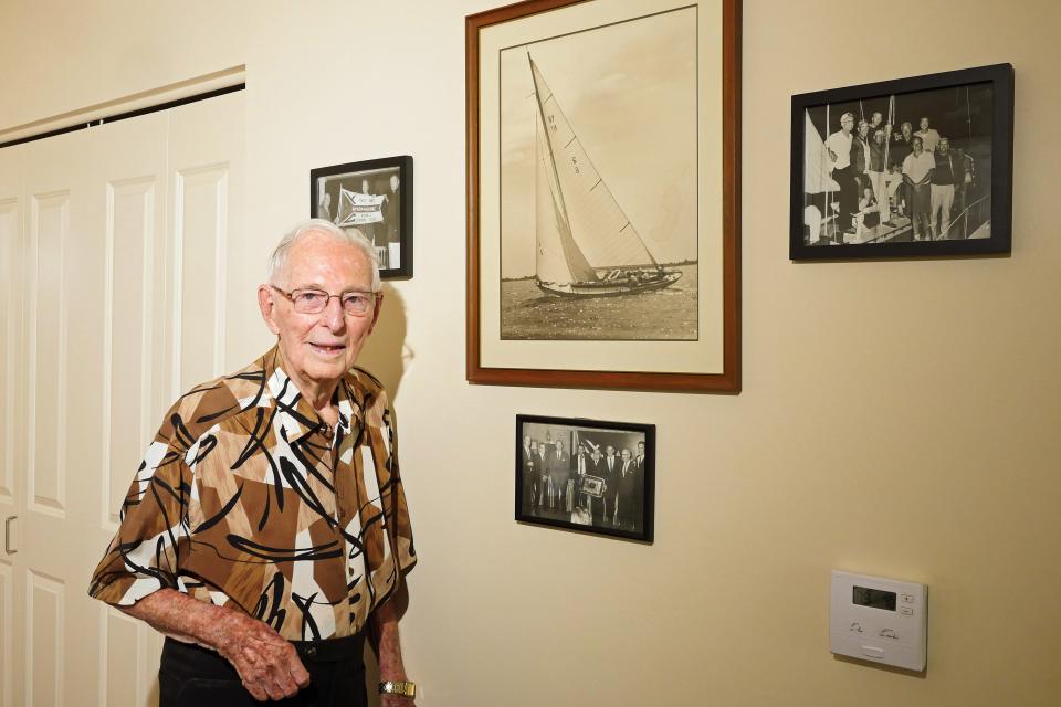 Jack Wagner stands near photos from the highlights of his career as a sailor on the Great Lakes, including a picture of him and the rest of the crew that won the overall cruising class of the 1962 Bayview-Mackinac race.